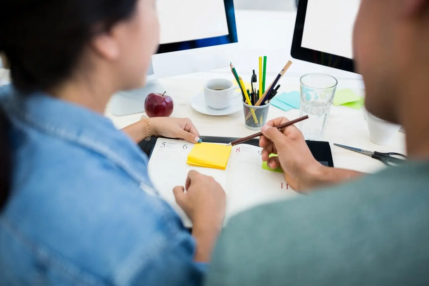 Un diseñador gráfico y una diseñadora gráfica escriben en un diario.